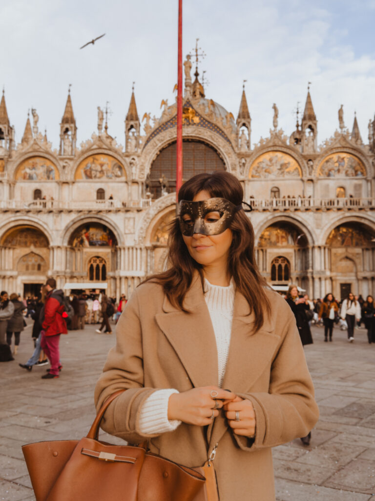 Carnival mask in St. Mark’s Square with St. Mark’s Basilica in Venice, Italy